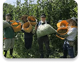 農園で収穫したものを持っている人たちの写真