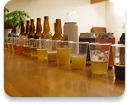 様々な色のビールがテーブルの上に一列に並んでいる写真